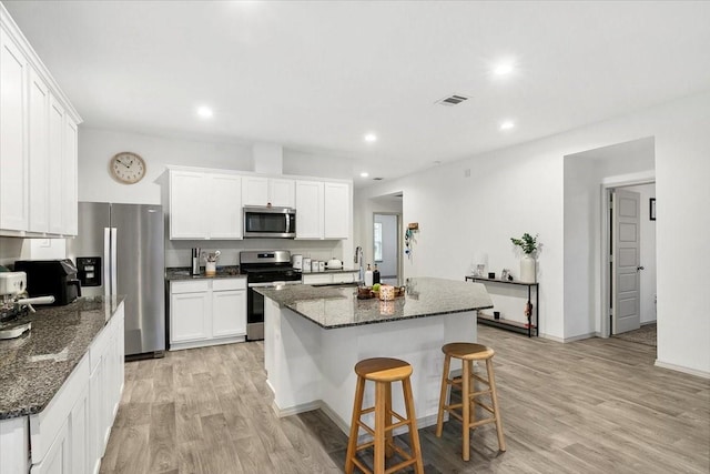 kitchen with a center island with sink, white cabinets, sink, light hardwood / wood-style flooring, and stainless steel appliances