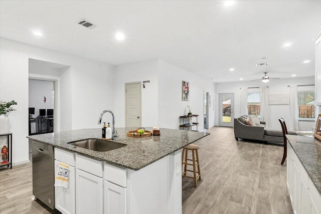 kitchen featuring dishwasher, white cabinets, a center island with sink, sink, and light hardwood / wood-style floors