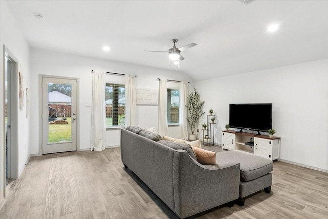 living room with ceiling fan, light hardwood / wood-style floors, and vaulted ceiling