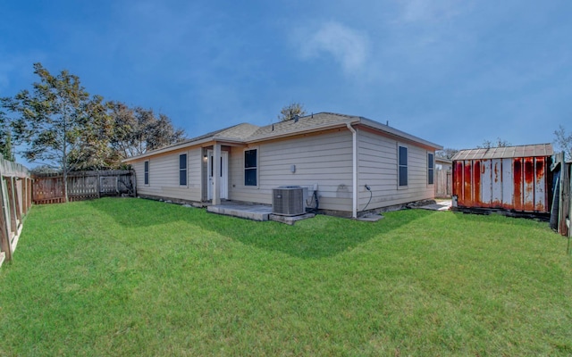 back of house with a yard, cooling unit, and a storage shed