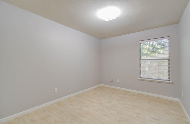 empty room with a textured ceiling and light hardwood / wood-style floors