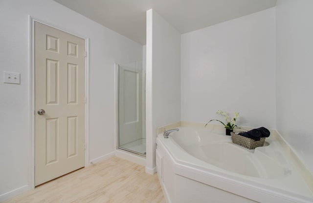 bathroom featuring wood-type flooring and shower with separate bathtub