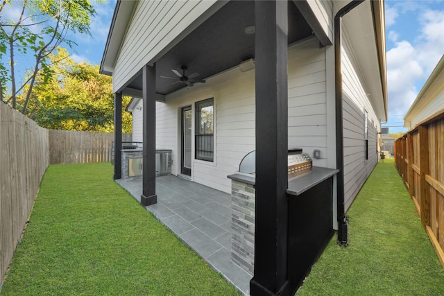 view of side of property with a lawn, a patio area, and ceiling fan