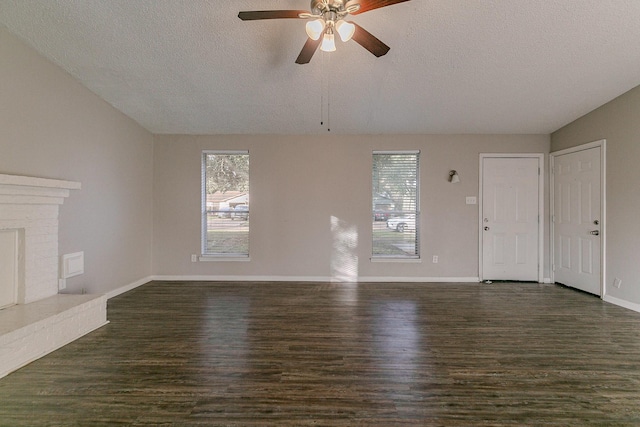 unfurnished living room with a fireplace, a textured ceiling, dark hardwood / wood-style floors, and ceiling fan