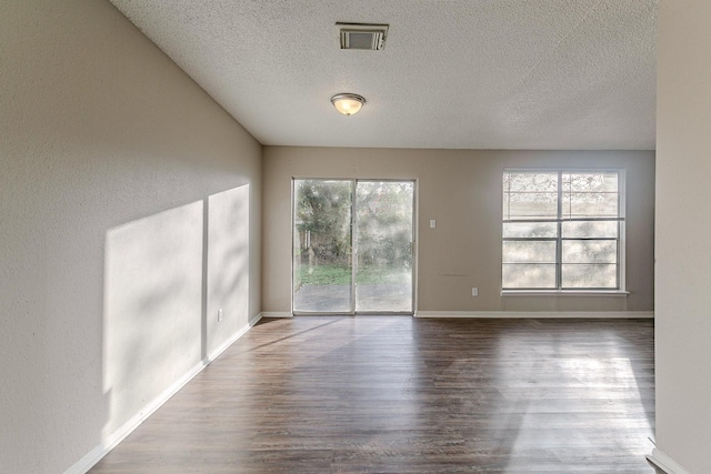 empty room with wood-type flooring and a textured ceiling