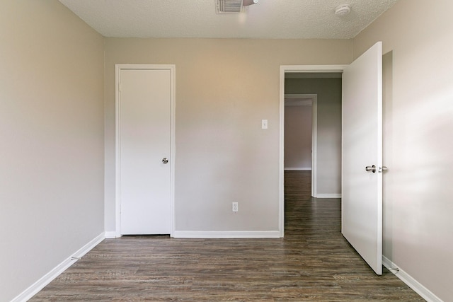 unfurnished bedroom featuring dark hardwood / wood-style floors and a textured ceiling