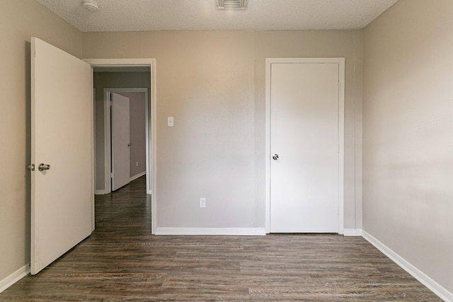 unfurnished bedroom with dark hardwood / wood-style flooring and a textured ceiling