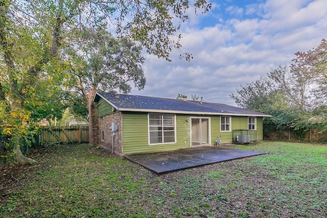 back of property with central air condition unit, a yard, and a patio