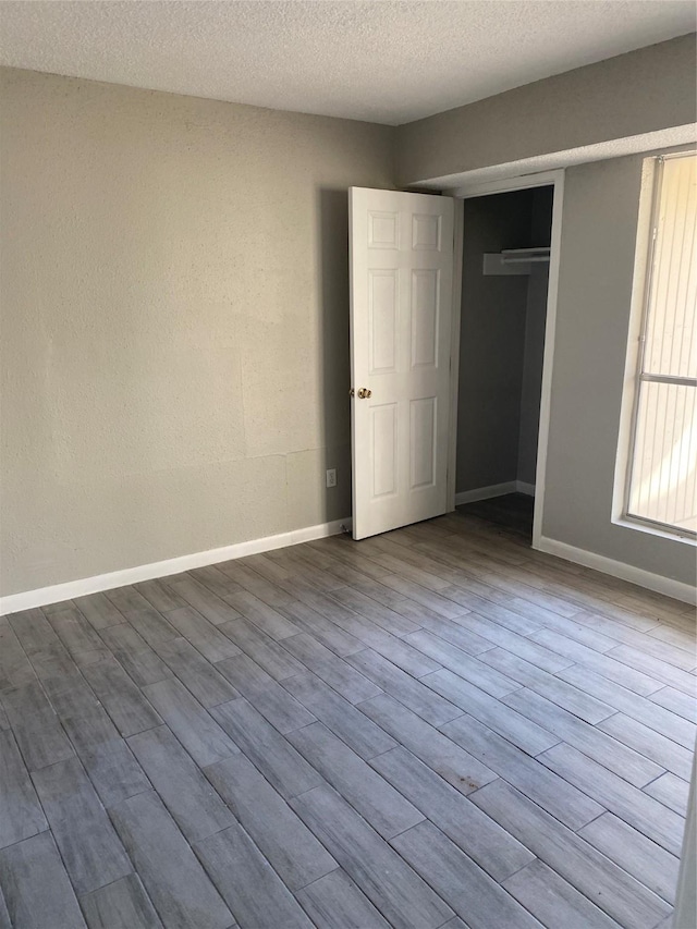 unfurnished bedroom with a textured ceiling, light wood-type flooring, and a closet