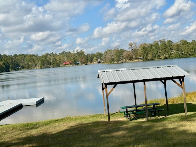 view of dock with a lawn and a water view