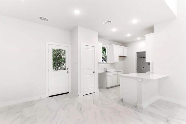 kitchen featuring a breakfast bar, refrigerator, white cabinetry, sink, and kitchen peninsula