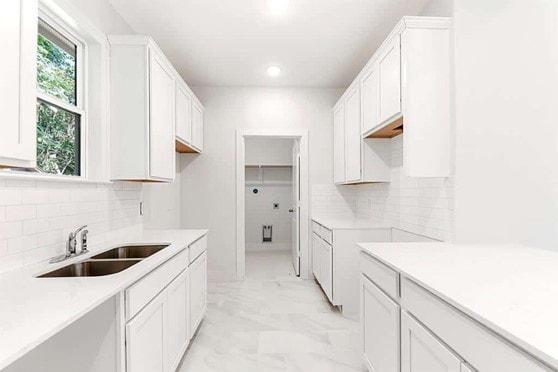 kitchen featuring sink, backsplash, and white cabinets