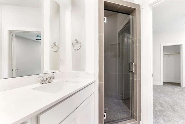 bathroom featuring a shower with door and vanity