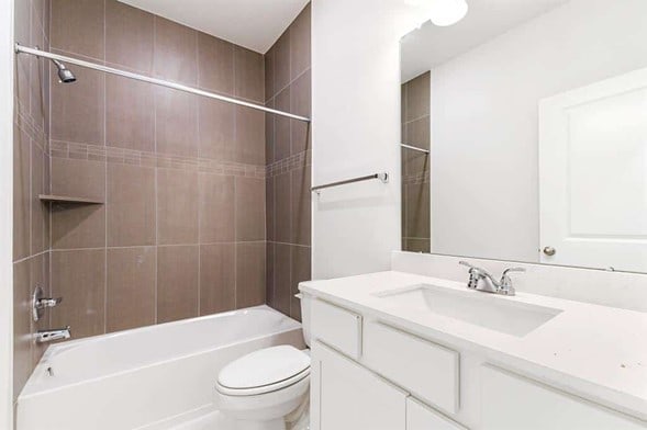 full bathroom featuring tiled shower / bath combo, vanity, and toilet