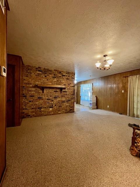 living room featuring brick wall, a textured ceiling, wooden walls, and a notable chandelier