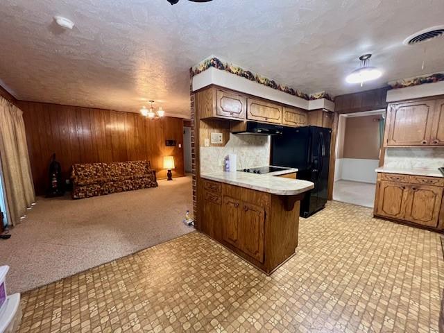 kitchen featuring tasteful backsplash, kitchen peninsula, wood walls, a breakfast bar, and black appliances