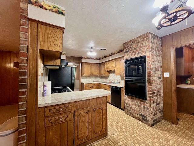 kitchen featuring black appliances, kitchen peninsula, and wooden walls