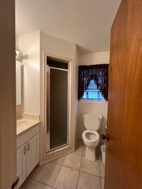 bathroom with tile patterned floors, vanity, toilet, and a shower with door