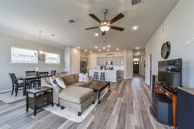 living room featuring light hardwood / wood-style flooring and ceiling fan with notable chandelier