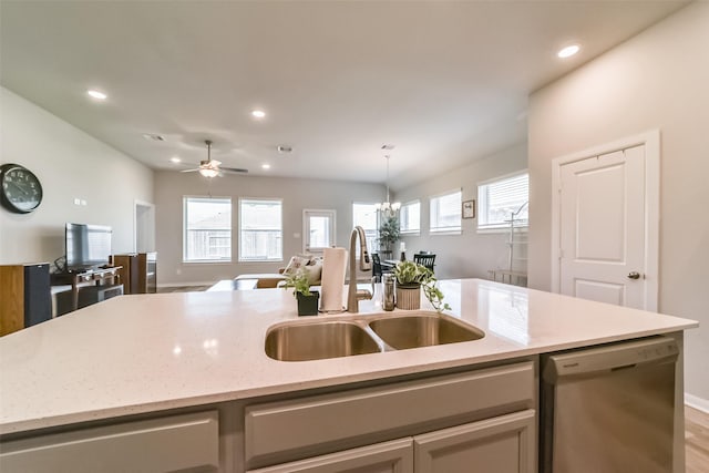 kitchen with dishwasher, ceiling fan with notable chandelier, sink, light hardwood / wood-style floors, and light stone counters