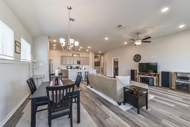 dining area with washer / clothes dryer, light hardwood / wood-style floors, and ceiling fan with notable chandelier