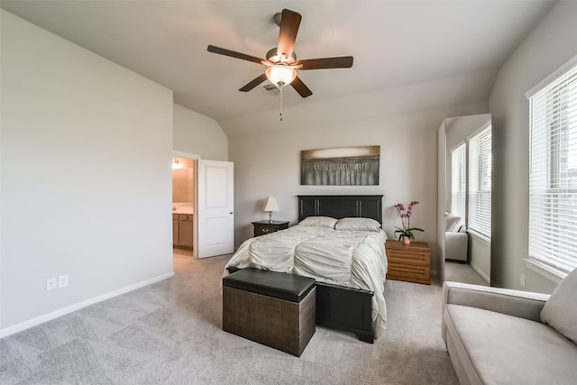 bedroom featuring light carpet, connected bathroom, vaulted ceiling, and ceiling fan