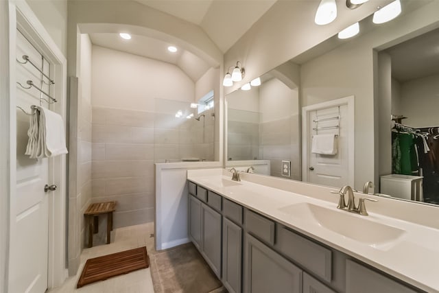 bathroom featuring a tile shower, tile patterned floors, lofted ceiling, vanity, and tile walls