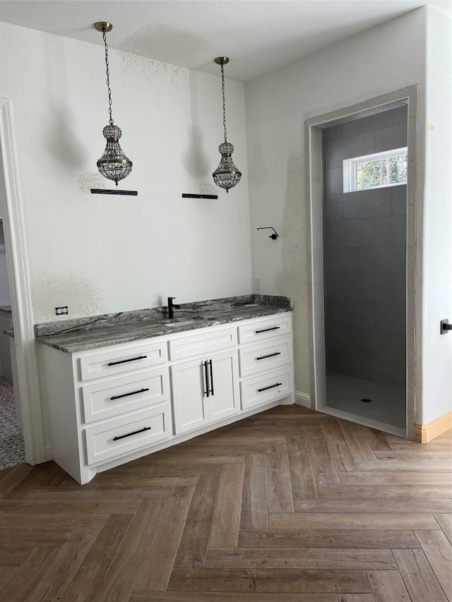 bathroom featuring vanity, parquet flooring, and a tile shower