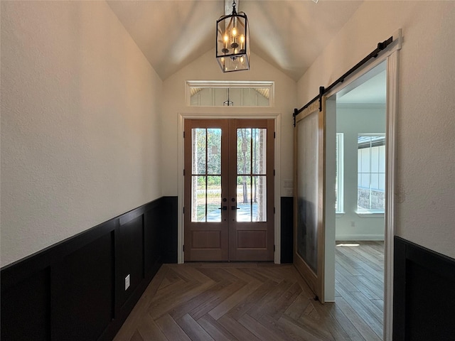 foyer with lofted ceiling, parquet floors, a barn door, and a healthy amount of sunlight