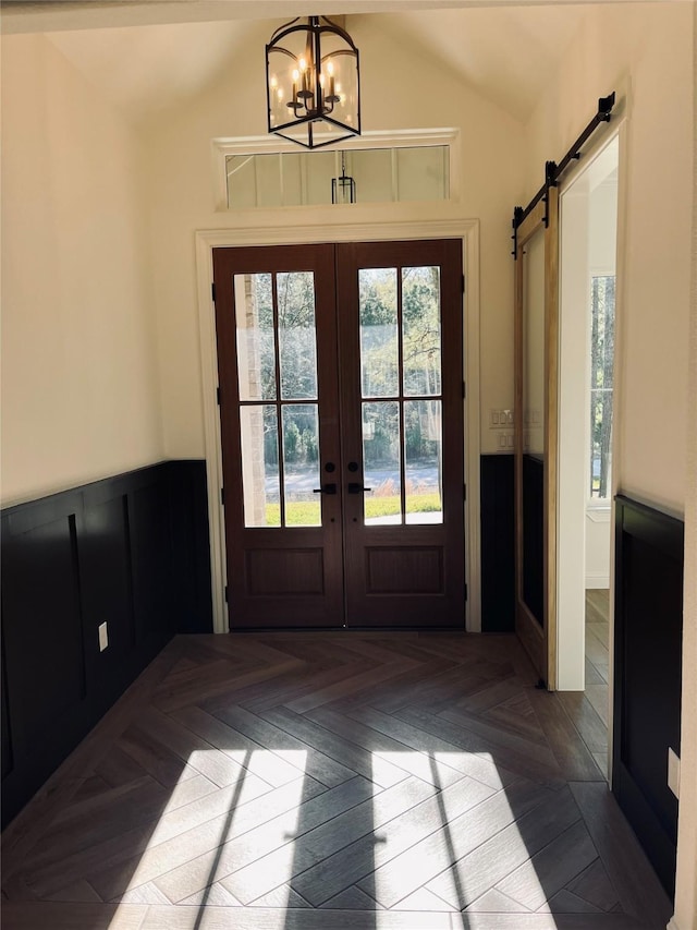 doorway with vaulted ceiling, parquet flooring, a barn door, an inviting chandelier, and french doors