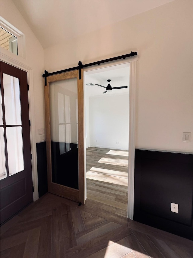 foyer with lofted ceiling, parquet floors, and a barn door