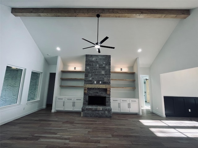 unfurnished living room featuring dark hardwood / wood-style floors, ceiling fan, a stone fireplace, and beamed ceiling