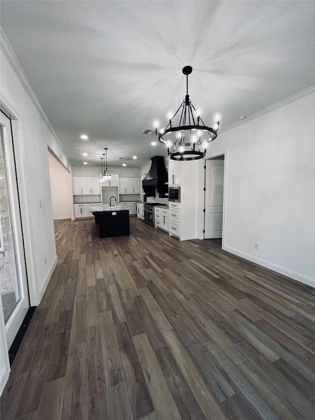 unfurnished living room with an inviting chandelier, dark hardwood / wood-style floors, crown molding, and sink