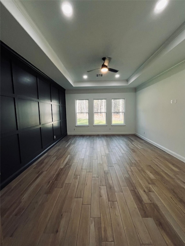 unfurnished room featuring hardwood / wood-style flooring, ceiling fan, and a raised ceiling