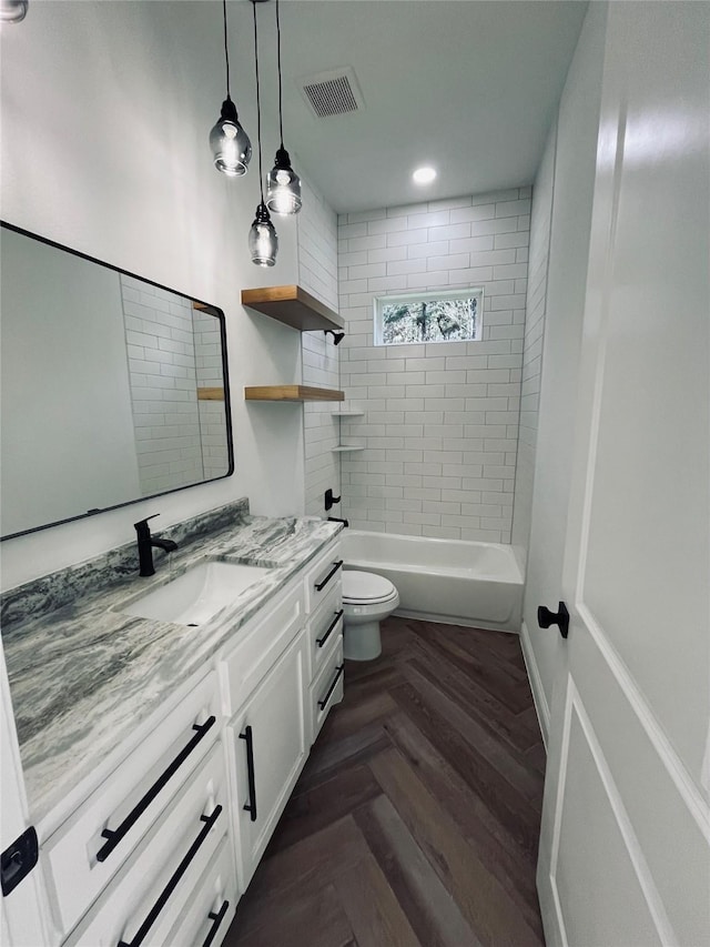 full bathroom featuring vanity, tiled shower / bath, parquet floors, and toilet