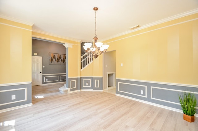 interior space with a chandelier, hardwood / wood-style flooring, ornate columns, and ornamental molding