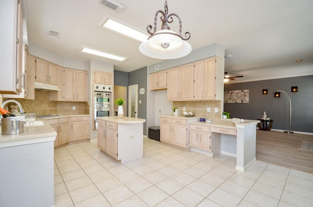 kitchen with ceiling fan, a center island, light brown cabinets, tasteful backsplash, and double oven