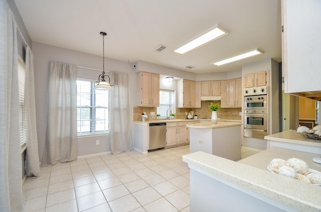 kitchen featuring light brown cabinets, backsplash, sink, appliances with stainless steel finishes, and a kitchen island