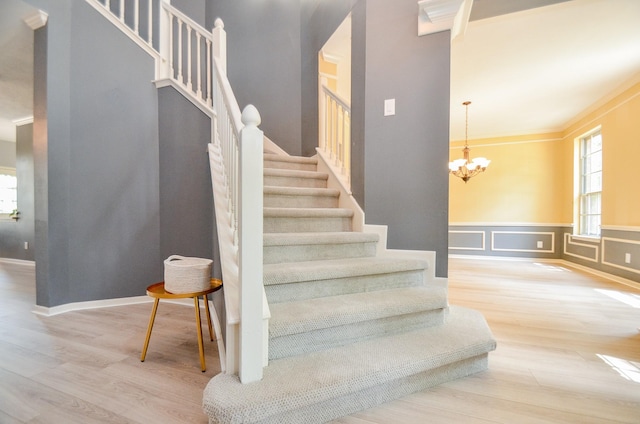 stairs with hardwood / wood-style floors, an inviting chandelier, and ornamental molding