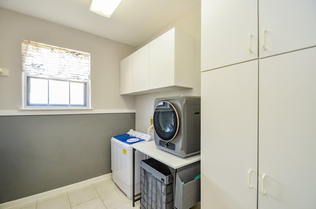 clothes washing area featuring cabinets and light tile patterned flooring