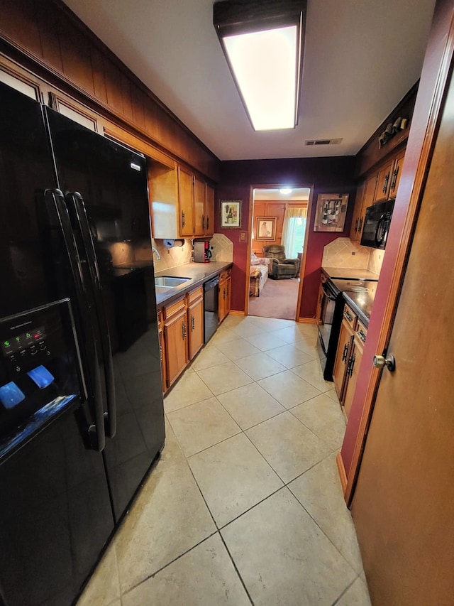 kitchen featuring light tile patterned floors, sink, and black appliances