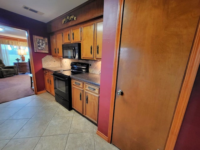 kitchen with decorative backsplash, light tile patterned floors, and black appliances