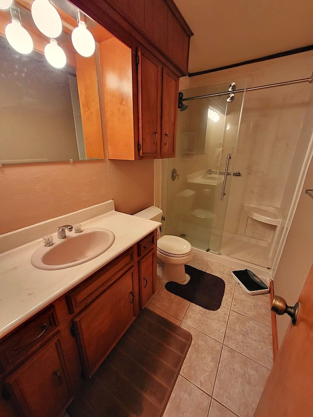 bathroom with tile patterned flooring, vanity, toilet, and a shower with shower door