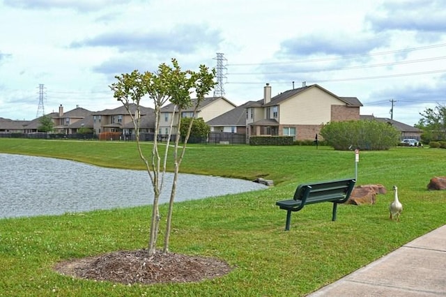 surrounding community with a water view and a yard