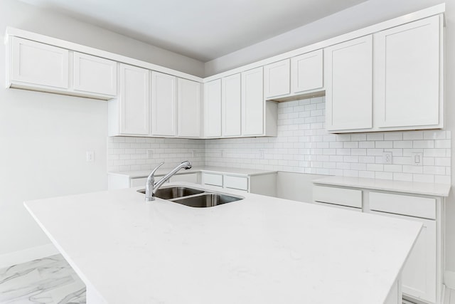 kitchen featuring tasteful backsplash, white cabinetry, and sink