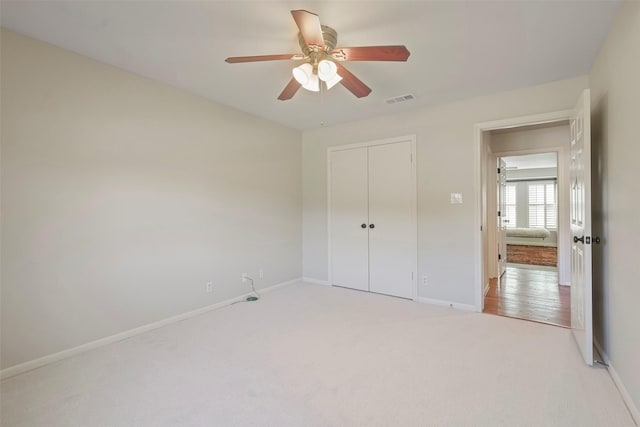 unfurnished bedroom featuring ceiling fan, a closet, and light colored carpet