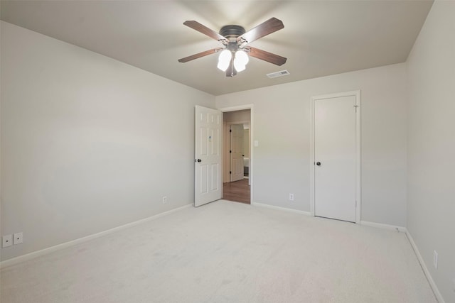 unfurnished bedroom featuring ceiling fan, light colored carpet, and a closet