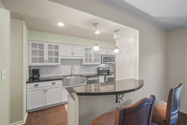 kitchen with sink, stainless steel appliances, decorative light fixtures, a breakfast bar area, and white cabinets