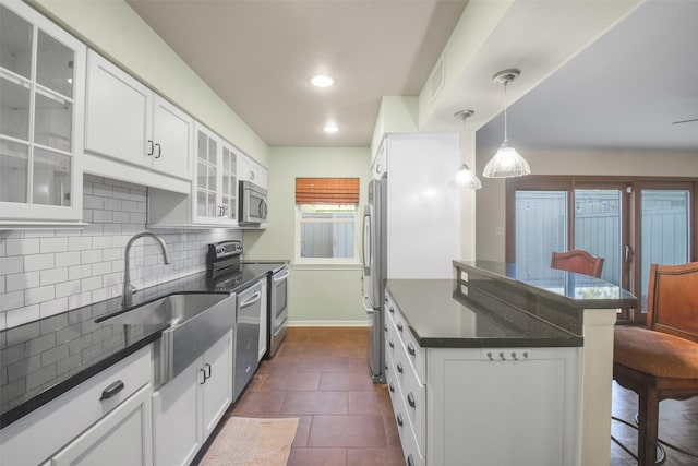 kitchen featuring a kitchen breakfast bar, backsplash, stainless steel appliances, dark tile patterned flooring, and white cabinetry