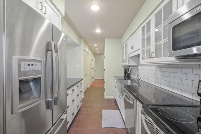 kitchen with decorative backsplash, stainless steel appliances, sink, dark tile patterned flooring, and white cabinets